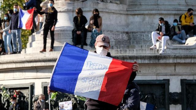 Ein Demonstrant mit der französische Flagge in den Händen. Auf der Flagge steht die Aufschrift "Redefreiheit".