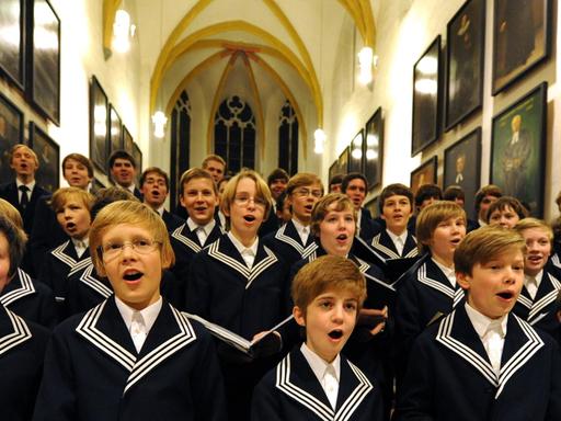 Mitglieder des Thomanerchores stehen in der Altarnische der Thomaskirche und singen mit Inbrunst.