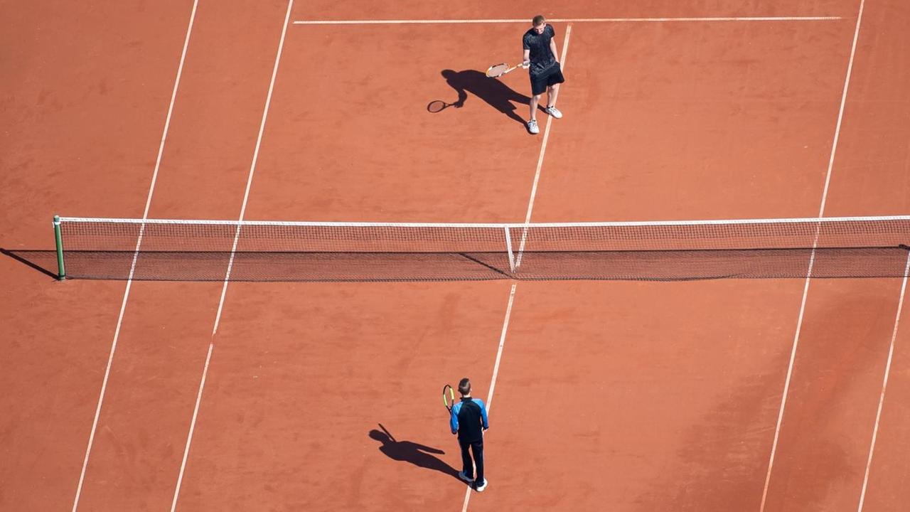 Zwei junge Männer stehen auf einem Tennisplatz. Zwei junge Männer stehen auf einem Tennisplatz.