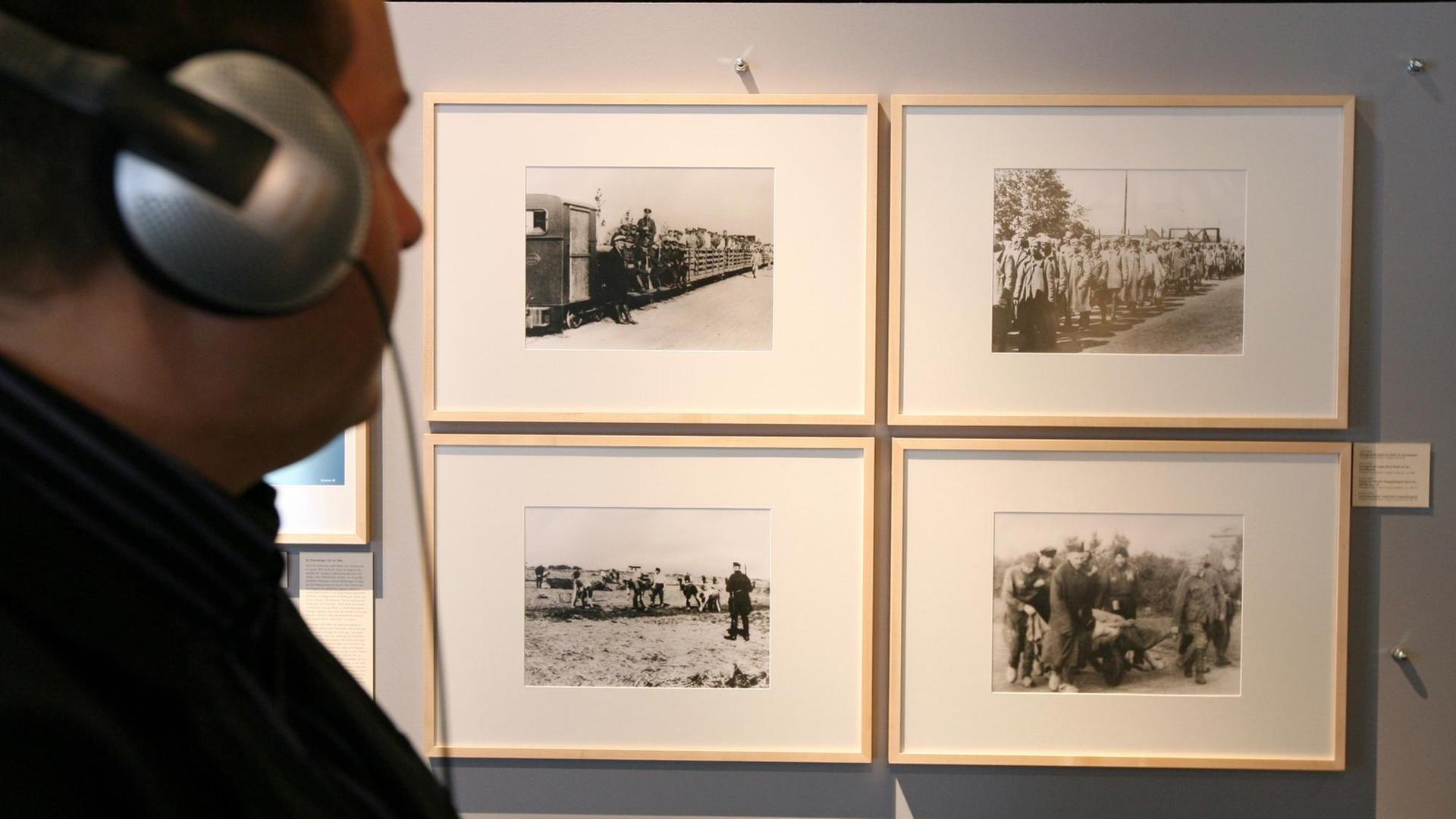 Ein Besucher steht im Emsland-Moormuseum vor Fotografien von Gefangenentransporten