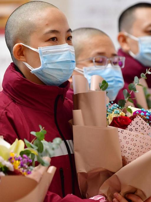 Chinesische Mitglieder eines medizinischen Einsatzteams im Kampf gegen das Coronavirus. Sie haben sich extra für den Schutzanzug die Haare abrasieren lassen.