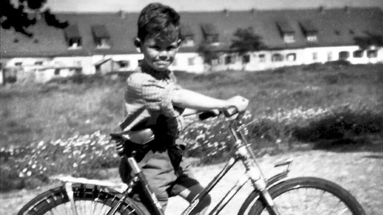 Ein Junge ist mit seinem Fahrrad unterwegs und schaut in die Kamera.