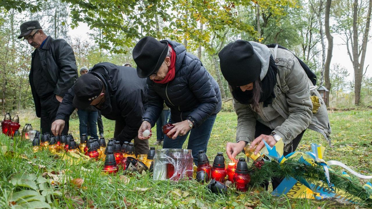 Polen und Ukrainer zünden Kerzen an an anderem zerstörten Denkmal in Monastirz in Ostpolen.
