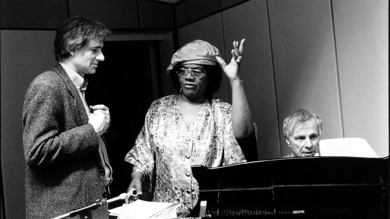Schwarzweißaufnahme von Vera Little mit Baskenmütze und buntem Kleid in einem Studio des Deutschlandradios. Schwarzweißaufnahme von Vera Little mit Baskenmütze und buntem Kleid in einem Studio des Deutschlandradios.