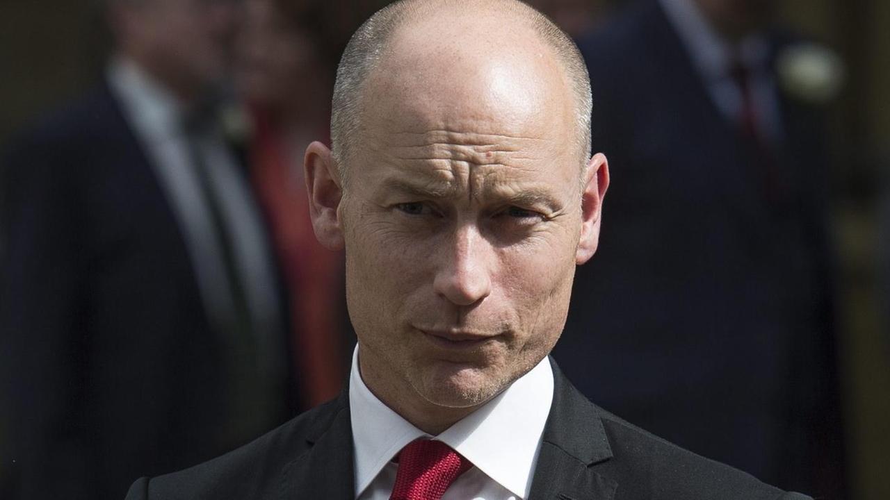 Stephen Kinnock mit schwarzem Anzug und Blume im Revers. Stephen Kinnock mit schwarzem Anzug und Blume im Revers.