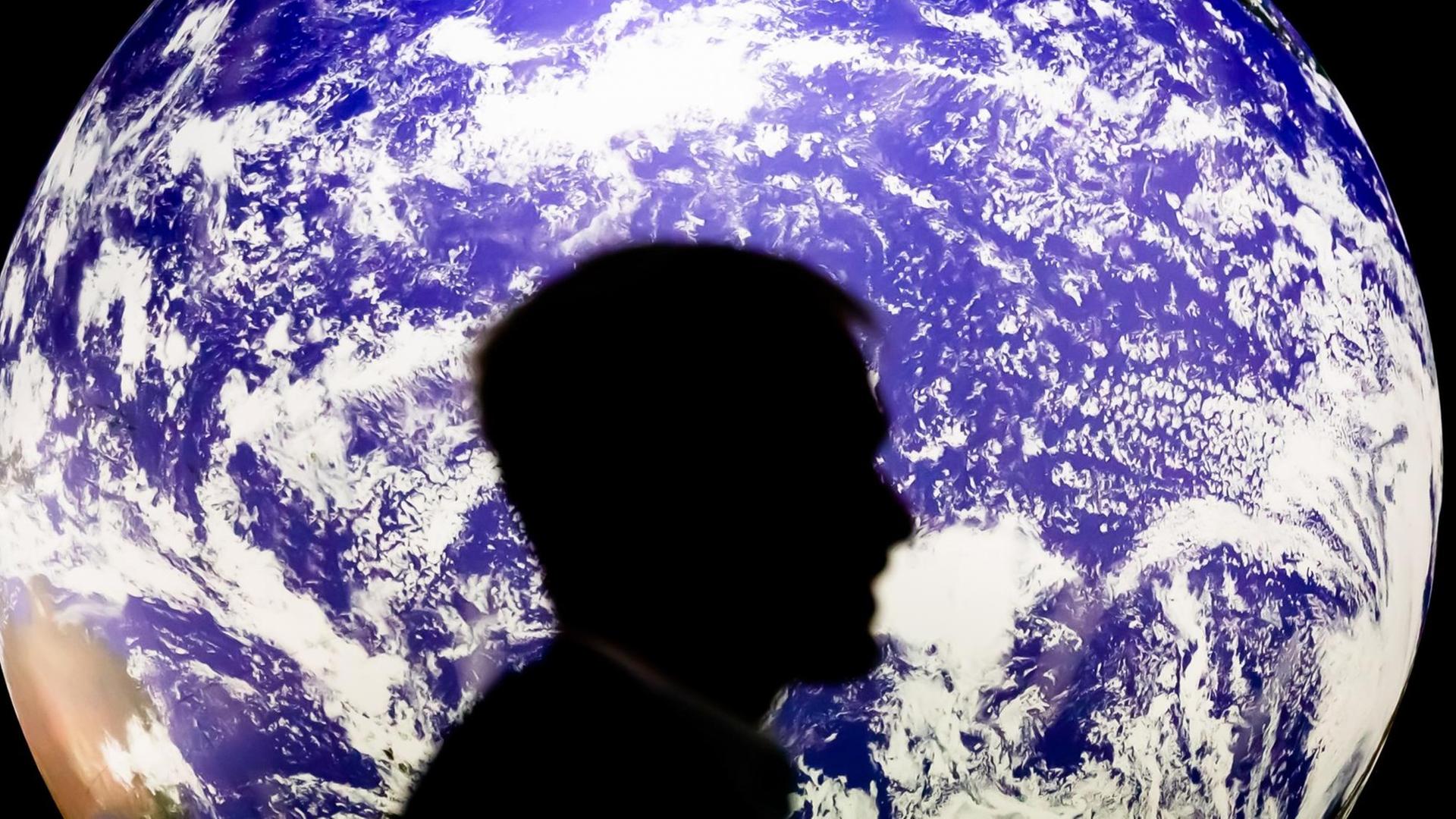 Ein Mann sitzt bei der UN-Klimakonferenz COP26 vor einem leuchtenden Globus. Ein Mann sitzt bei der UN-Klimakonferenz COP26 vor einem leuchtenden Globus.
