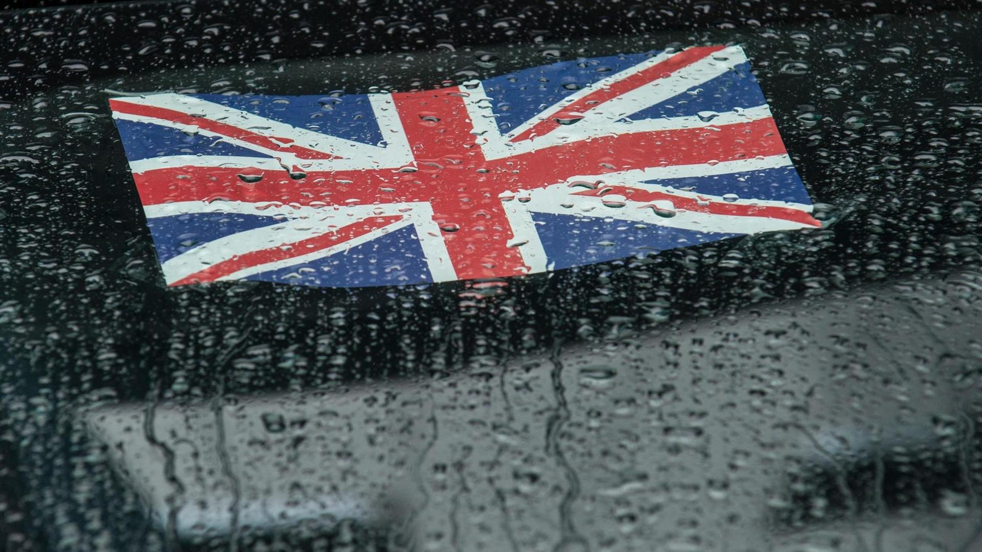 Die britische Flagge klebt an einer Autoscheibe mit Regentropfen Die britische Flagge klebt an einer Autoscheibe mit Regentropfen