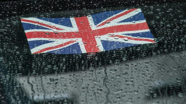 Die britische Flagge klebt an einer Autoscheibe mit Regentropfen