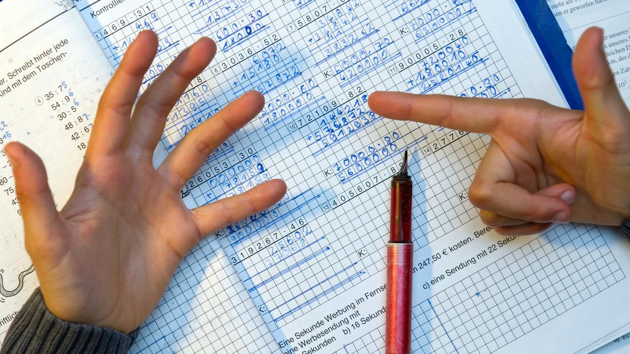 Ein Grundschüler nimmt bei den Hausaufgaben im Fach Mathematik seine Finger zur Hilfe. Ein Grundschüler nimmt bei den Hausaufgaben im Fach Mathematik seine Finger zur Hilfe.