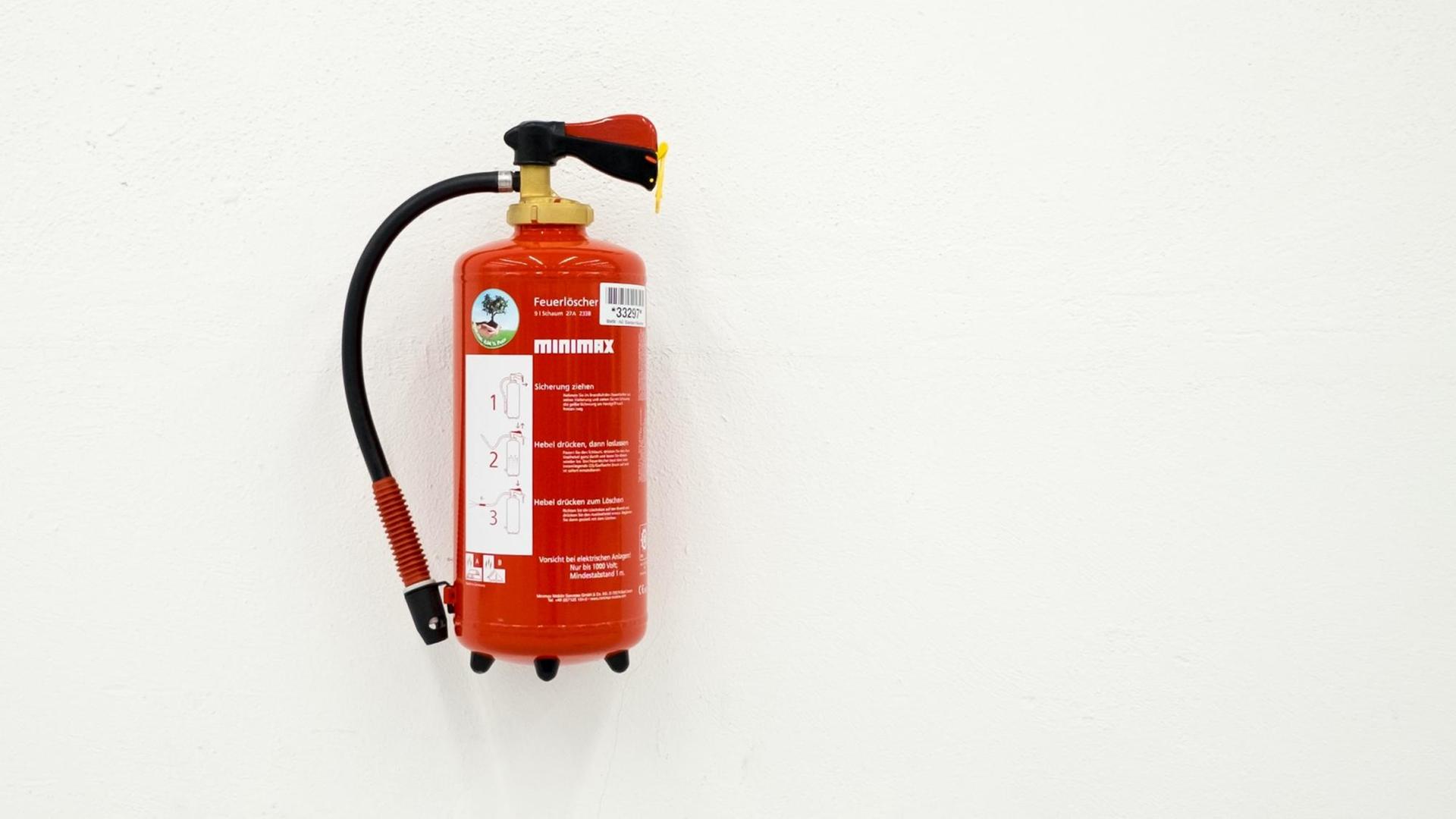 Roter Feuerlöscher an einer weißen Wand Roter Feuerlöscher an einer weißen Wand