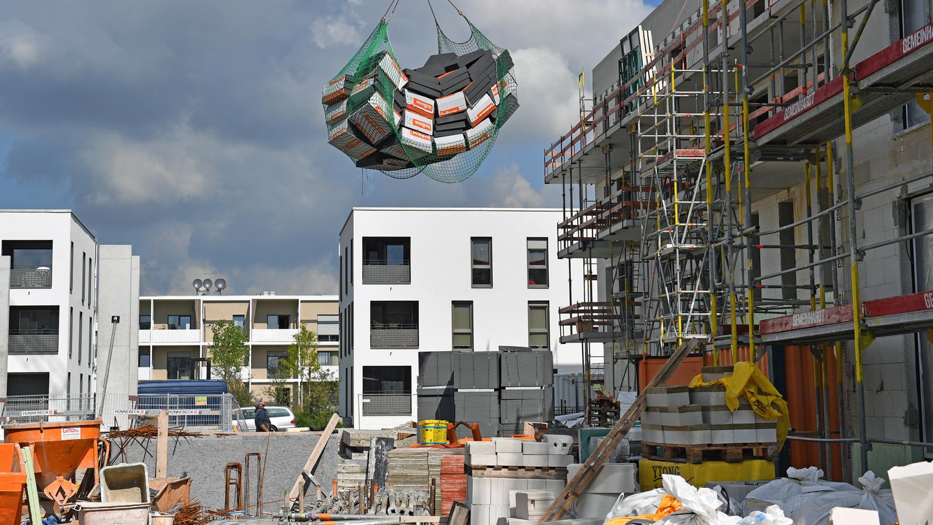 Wohnungsbau in München: Dämmplatten werden über eine Baustelle gehoben. Wohnungsbau in München: Dämmplatten werden über eine Baustelle gehoben.