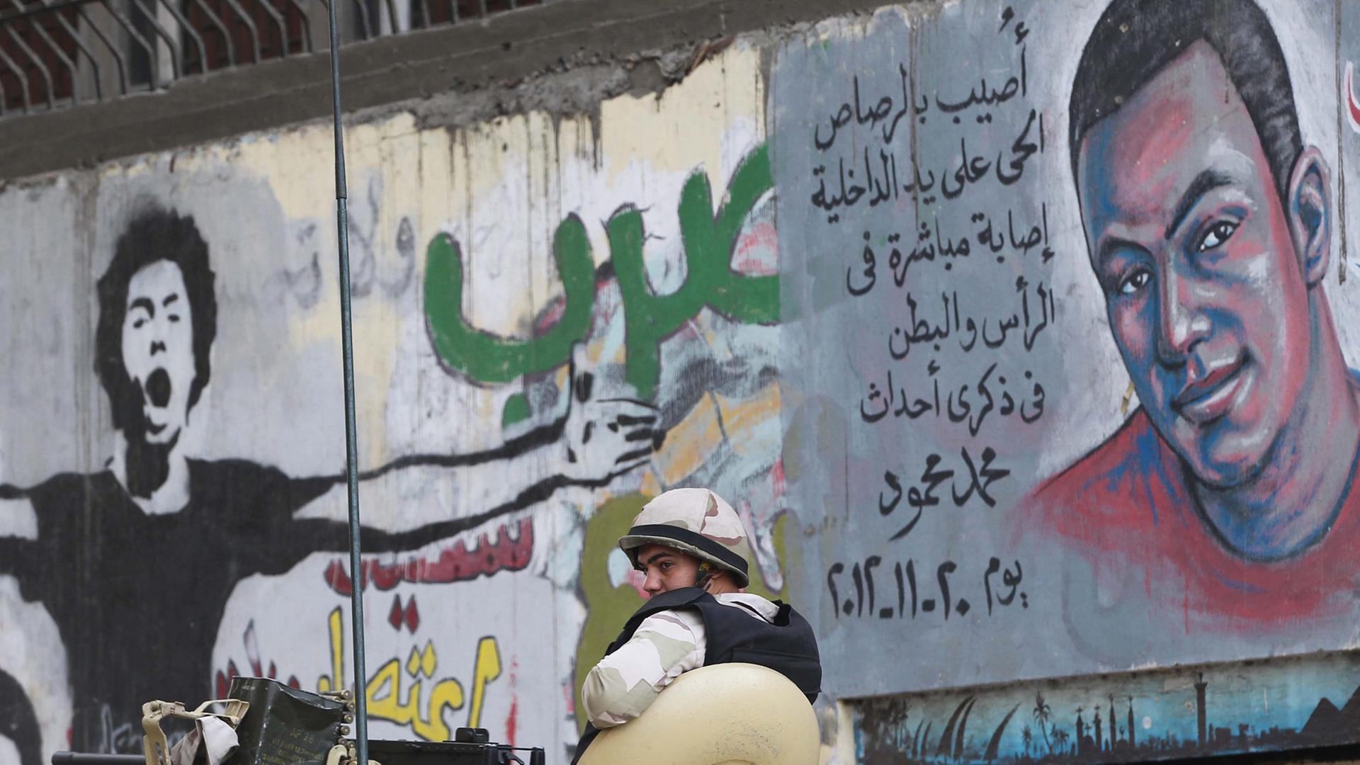 Ein ägyptischer Soldat vor einer Wand in Kairo, mit Graffits von Opfern gewaltsamer Zusammenstöße.