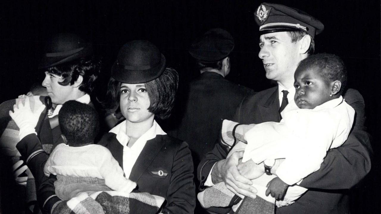 Bei der Ankunft am Flughafen Basel tragen zwei Flugbegleiterinnen und der Kapitän Biafra-Babys auf dem Arm, die in die Schweiz ausgeflogen wurden.