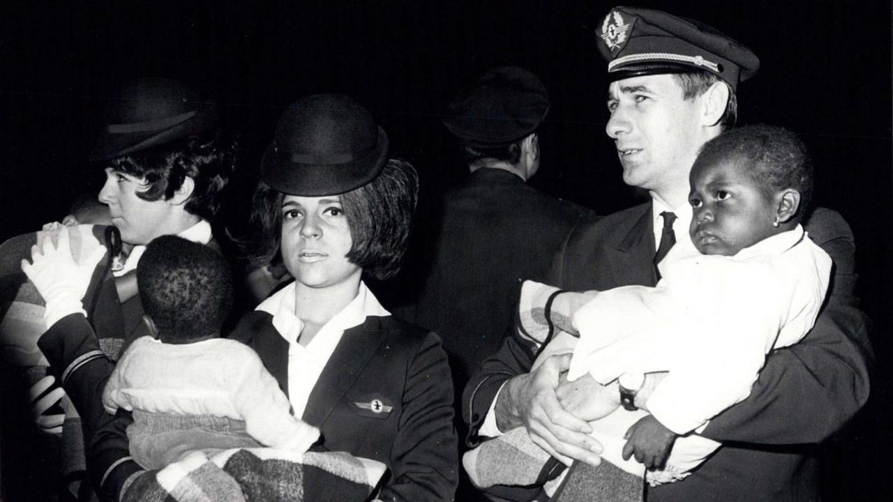 Bei der Ankunft am Flughafen Basel tragen zwei Flugbegleiterinnen und der Kapitän Biafra-Babys auf dem Arm, die in die Schweiz ausgeflogen wurden. Bei der Ankunft am Flughafen Basel tragen zwei Flugbegleiterinnen und der Kapitän Biafra-Babys auf dem Arm, die in die Schweiz ausgeflogen wurden.