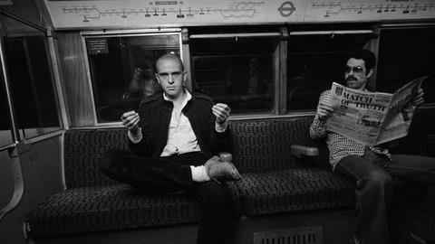 Peter Gabriel imitiert einen Zeitungsleser in der Londoner U-Bahn 1978.