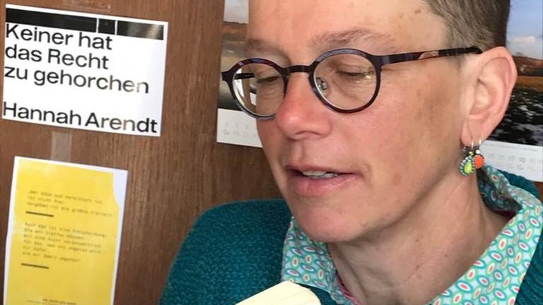 Eine Frau im Halbprofil und mit kurzen Haaren liest in einem Buch. Eine Frau im Halbprofil und mit kurzen Haaren liest in einem Buch.