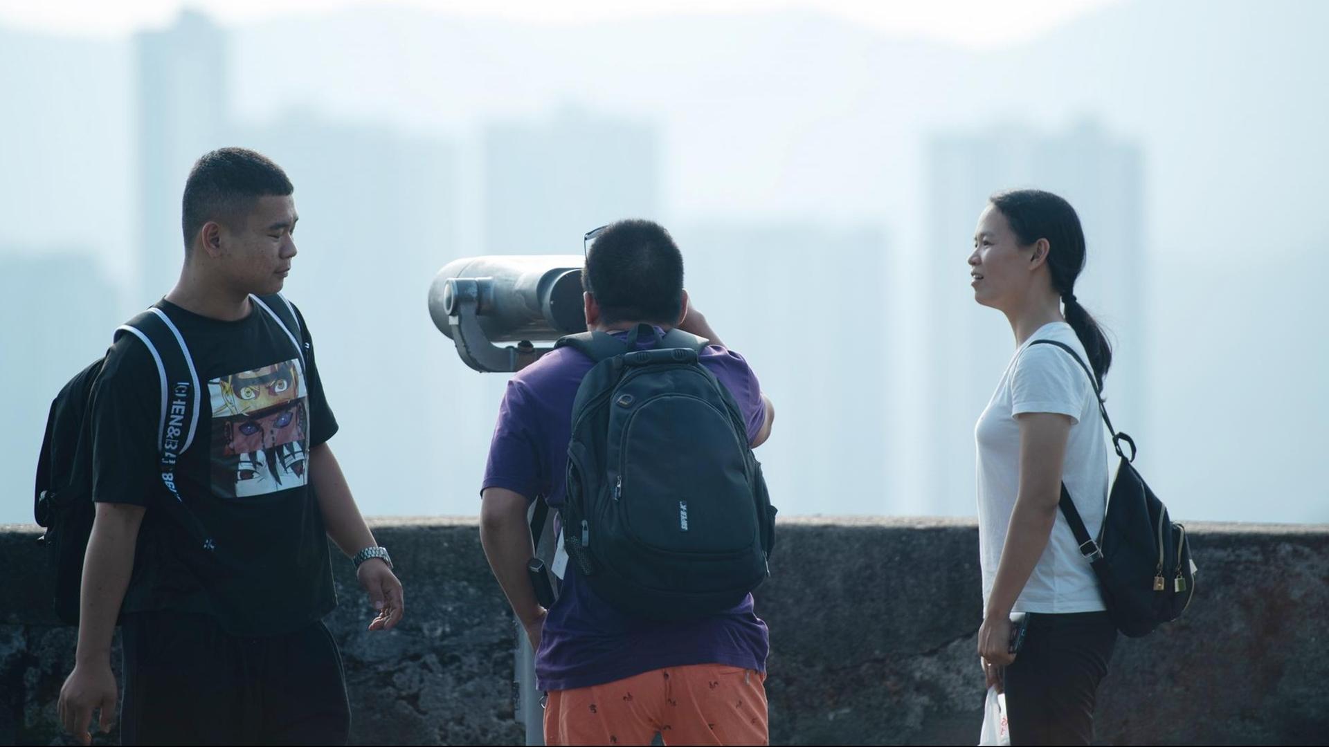 Junge Touristen besichtigen Mount Fortress in Macao und schauen durch ein Fernrohr. Junge Touristen besichtigen Mount Fortress in Macao und schauen durch ein Fernrohr.