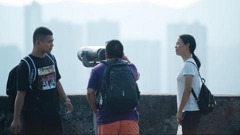 Junge Touristen besichtigen Mount Fortress in Macao und schauen durch ein Fernrohr.