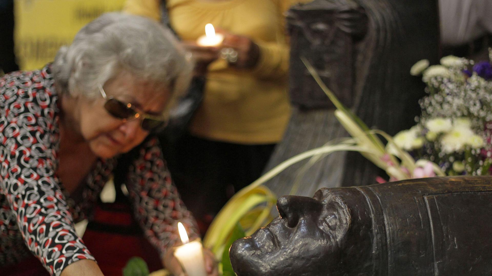 Eine Frau besucht das Grab von Erzbischof Romero in San Salvador anlässlich seines 33. Todestages.