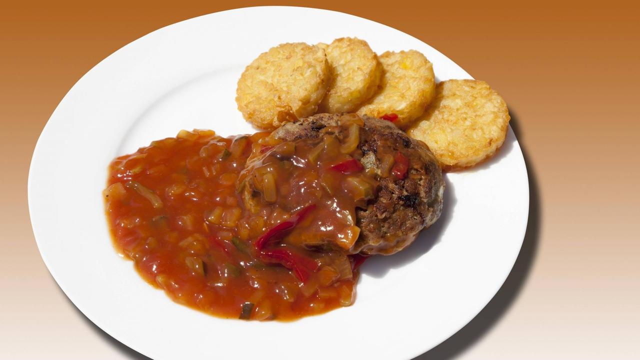Ein deftiges Gericht auf einem Teller: Hackbraten mit "Zigeunersauce" und Kartoffelrösti.