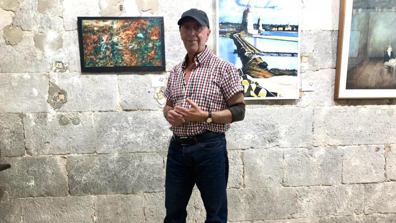 Gino Sanguinetti steht vor Gemälden. Gino Sanguinetti steht vor Gemälden.