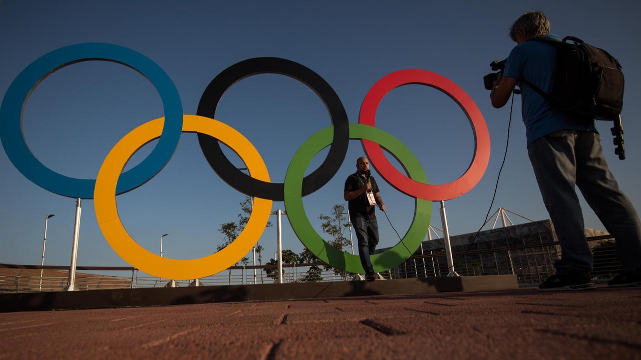Ein Fernsehjournalist wird vor den Olympischen Ringen in Rio de Janeiro gefilmt.