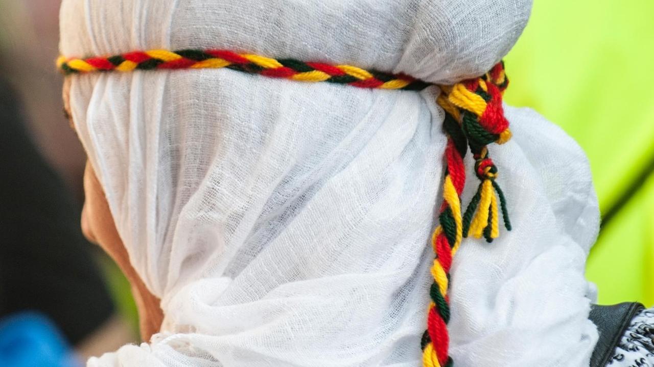 Ein Frau trägt ein Haarband in der Farben Kurdistans