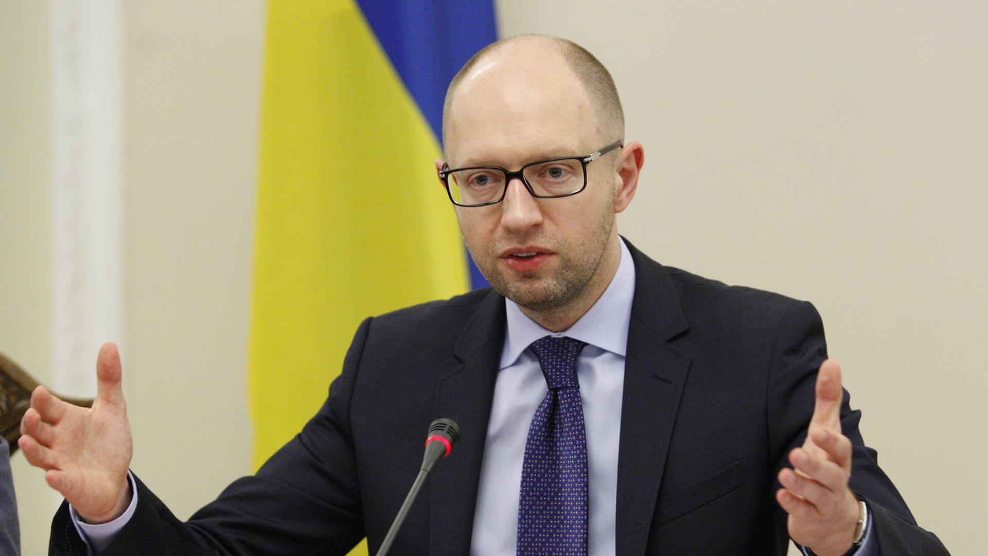 Der ukrainische Premierminister Arseni Jazenjuk sitzt an einem Tisch hinter einem Mikrofon und gestikuliert. Der ukrainische Premierminister Arseni Jazenjuk sitzt an einem Tisch hinter einem Mikrofon und gestikuliert.