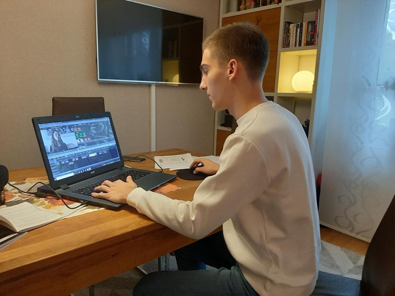Paul Fiedler sitzt an seinem Laptop und verarbeitet das gesammelte Filmmaterial. Er trägt einen weißen Pullover und schaut auf seinen Bildschirm. Paul Fiedler sitzt an seinem Laptop und verarbeitet das gesammelte Filmmaterial. Er trägt einen weißen Pullover und schaut auf seinen Bildschirm.