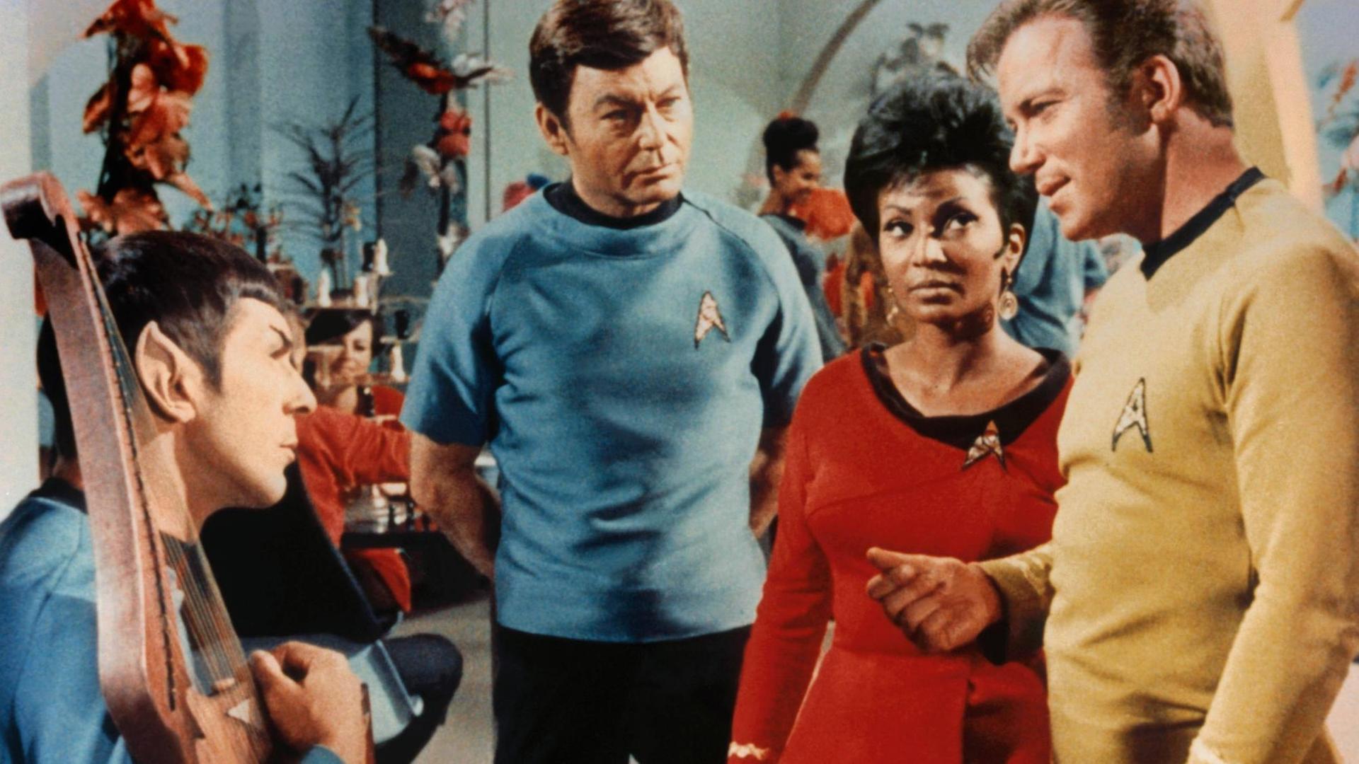 Szene aus der US-Fernsehserie "Star Trek" (1966-1969): Die Schwarze Schauspielerin Nichelle Nichols sowie die Schauspieler Leonard Nimoy, Deforest Kelley und William Shatner sprechen miteinander.