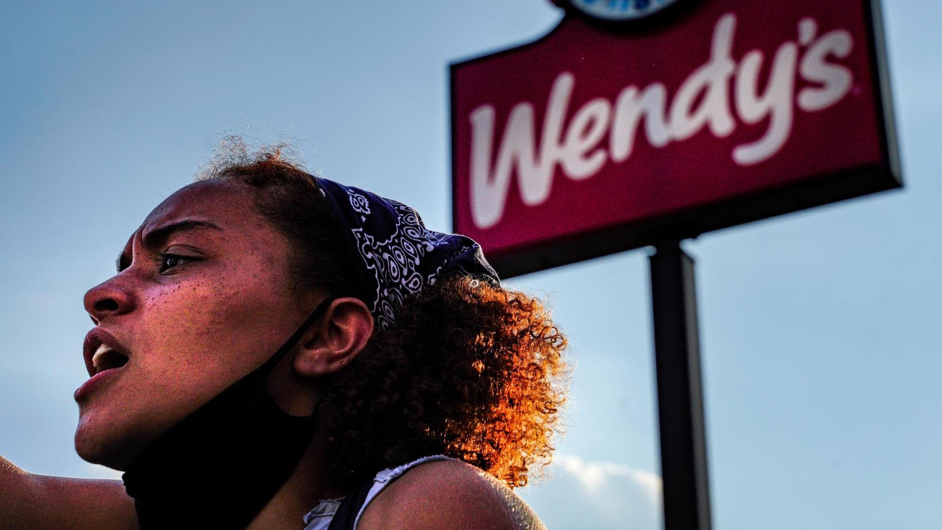 Eine Demonstrantin steht vor einem Schild der Restaurantkette Wendys Eine Demonstrantin steht vor einem Schild der Restaurantkette Wendys