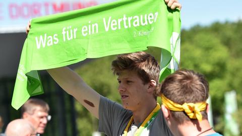 Ein junger Mann hält während des Evangelischen Kirchentages in Dortmund vor der Westfalenhalle einen grünen Schal mit der Aufschrift «Was für ein Vertrauen» hoch. Gut 2000 Veranstaltungen sind bis zum 23. Juni 2019 geplant, zahlreiche Politiker und Prominente nehmen teil.