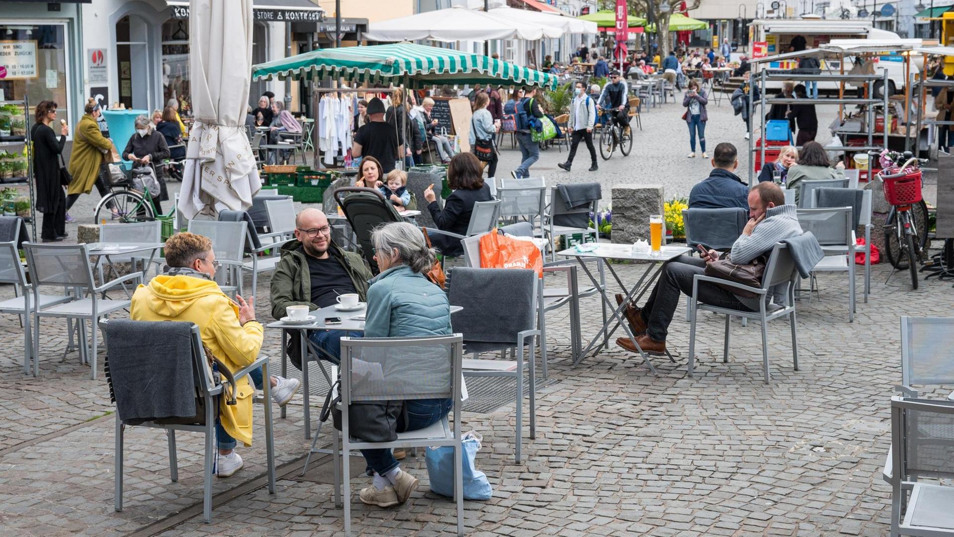 Auf dem St. Johanner Markt in Saarbrücken sitzen Menschen im Außenbereich von Gastronomiebetrieben.