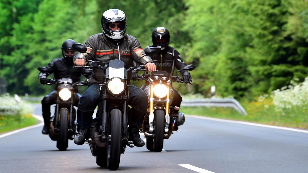 Drei Motorradfahrer in voller Montur fahren auf einer Straße Drei Motorradfahrer in voller Montur fahren auf einer Straße