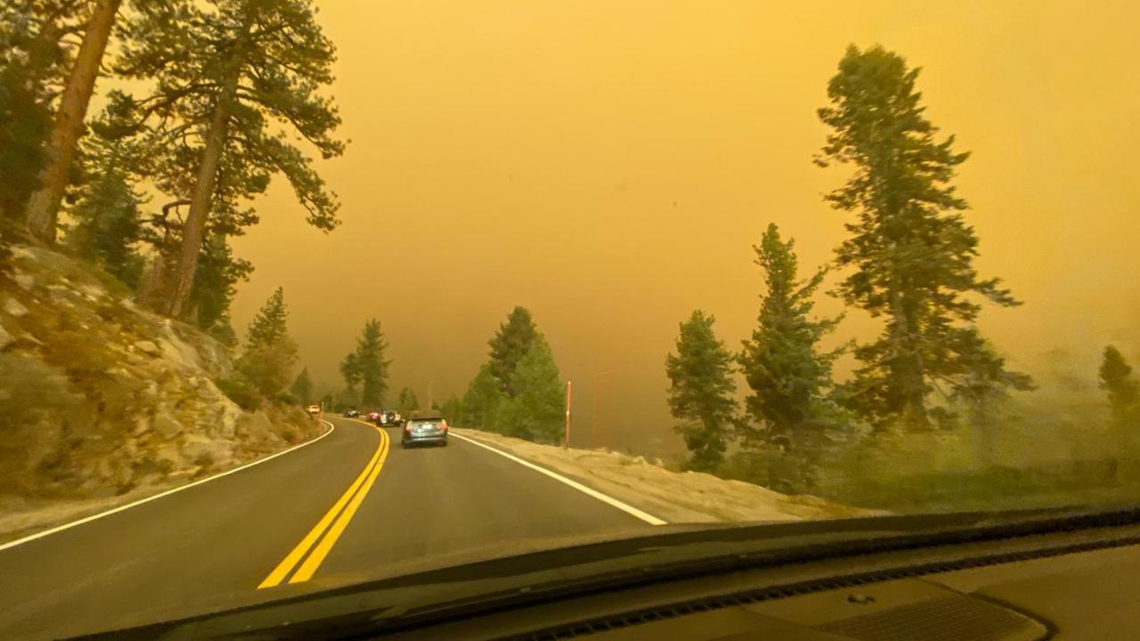 Blick aus dem Autofenster auf die Straße: Im Hintergrund von Flammen orangener Himmel.