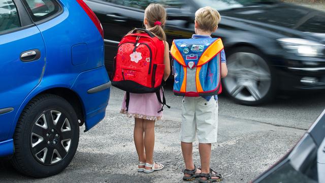 Zwei Kinder üben vor ihrer Einschulung das richtige Überqueren einer Straße auf ihrem künftigen Schulweg.