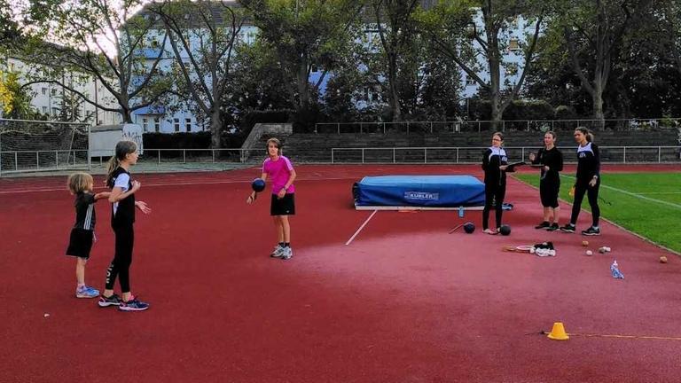Junge Mädchen üben mit coronabedingtem Abstand auf einem Sportplatz im Freien. Junge Mädchen üben mit coronabedingtem Abstand auf einem Sportplatz im Freien.