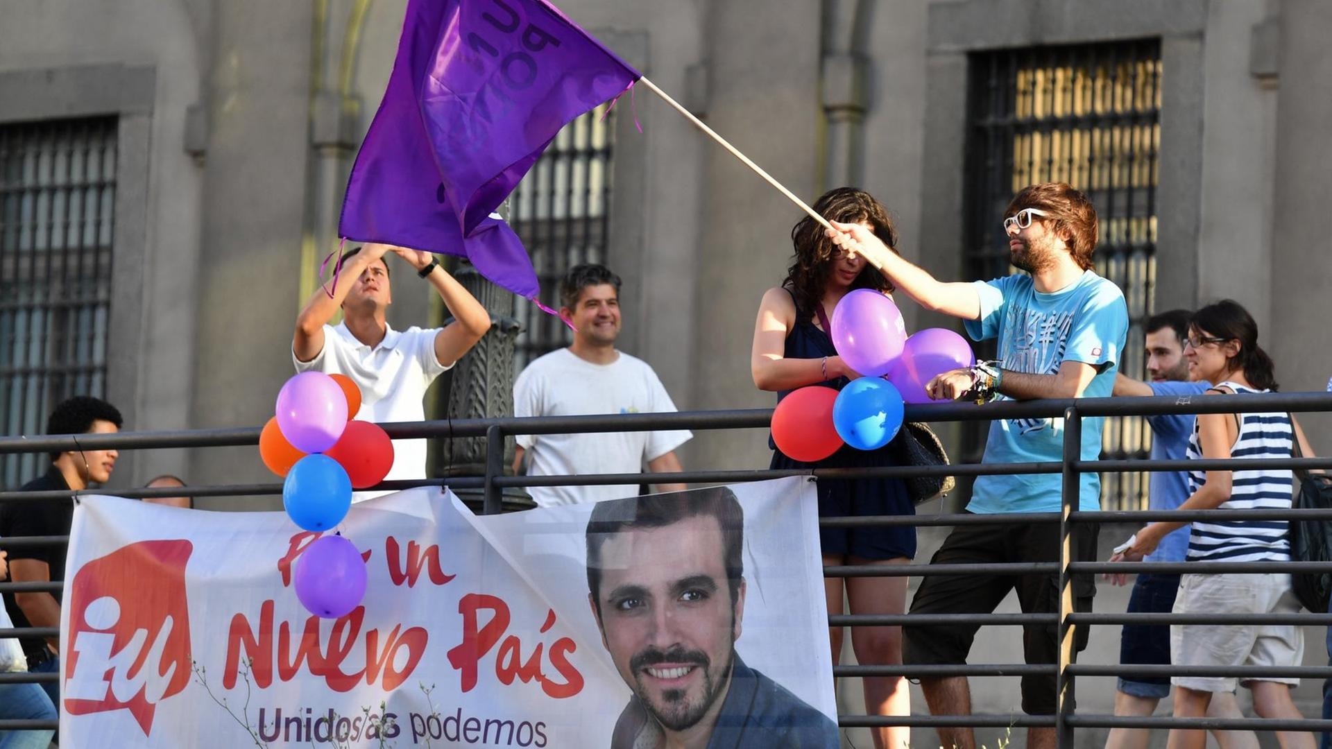 Ein Anhänger der linken Podemos-Partei schwenkt am Wahltag in Madrid eine Fahne.