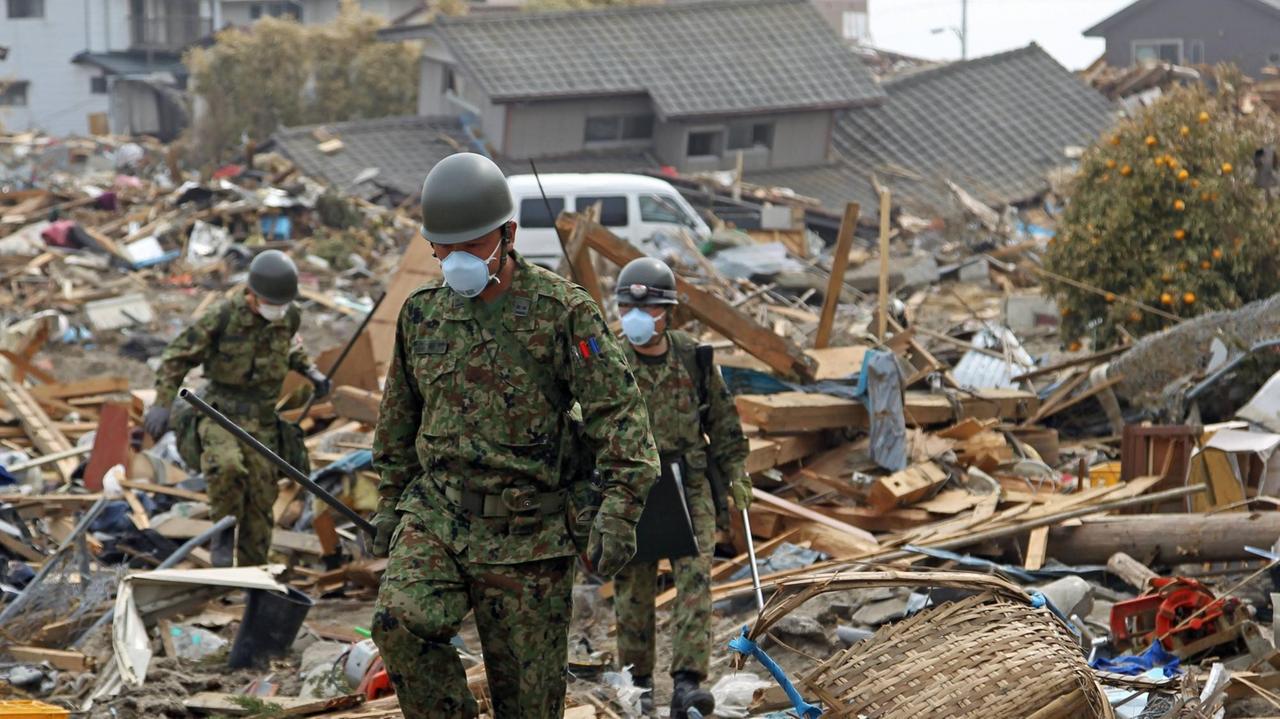 Mitglieder der japanischen Selbstverteidigungsstreitkräfte suchen am 2. April 2011, wenige Tage nach dem heftigsten Erdbeben in der Geschichte Japans, in Iwaki, einer Großstadt in der Präfektur Fukushima, nach Überlebenden