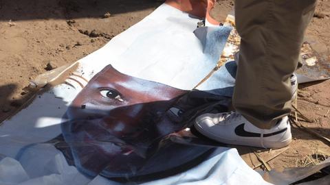 Jemand steht auf dem am Boden liegenden Wahlplakat des abgewählten gambischen Präsidenten Jammeh