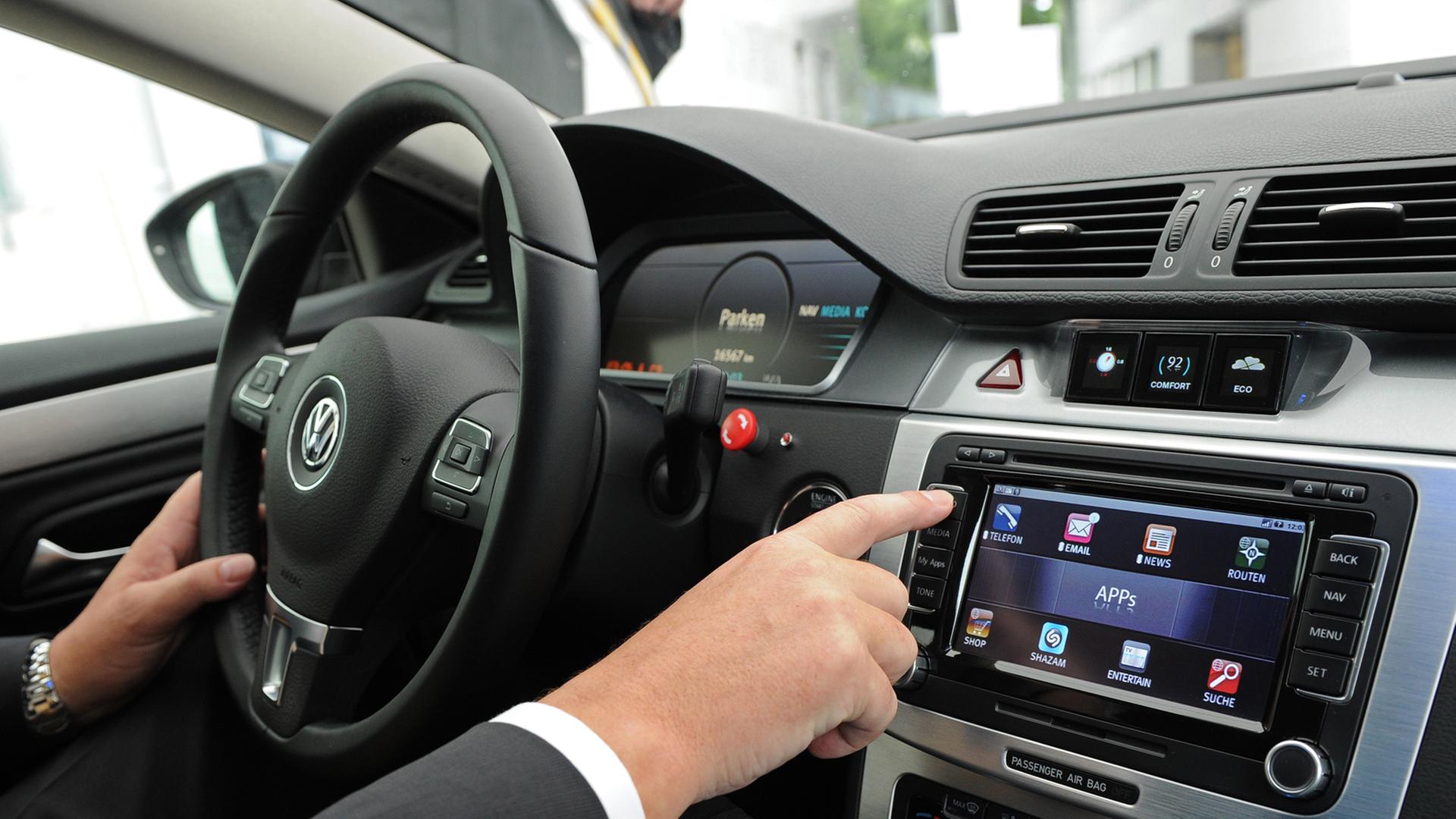 Ein Autofahrer bedient den Bordcomputer seines Fahrzeugs. Ein Autofahrer bedient den Bordcomputer seines Fahrzeugs.
