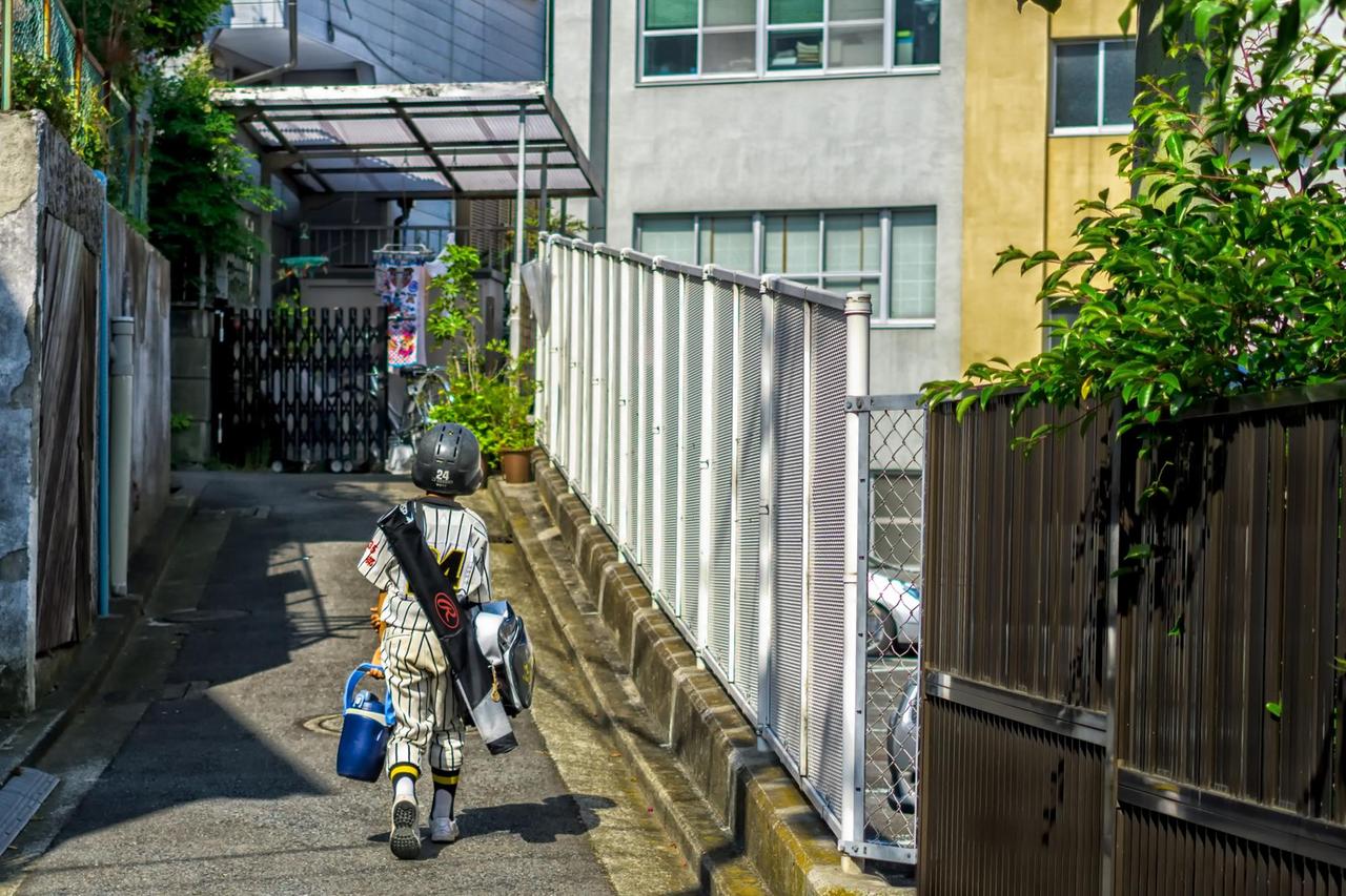 Ein kleiner Junge in Baseballuniform und Ausrüstung auf dem Weg nach Hause. Ein kleiner Junge in Baseballuniform und Ausrüstung auf dem Weg nach Hause.