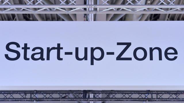 Mit einem Schild wird auf eine Start-Up-Zone in einer Messehalle der Leipziger Messe hingewiesen.