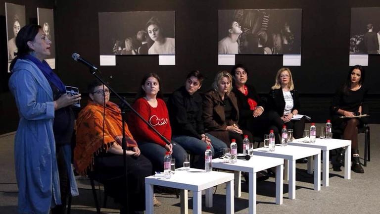 Große schwarz-weiße Fotos mit Gesichtern der "Kinder des Krieges", davor eine Sitzgruppe mit betroffenen Müttern und Töchtern