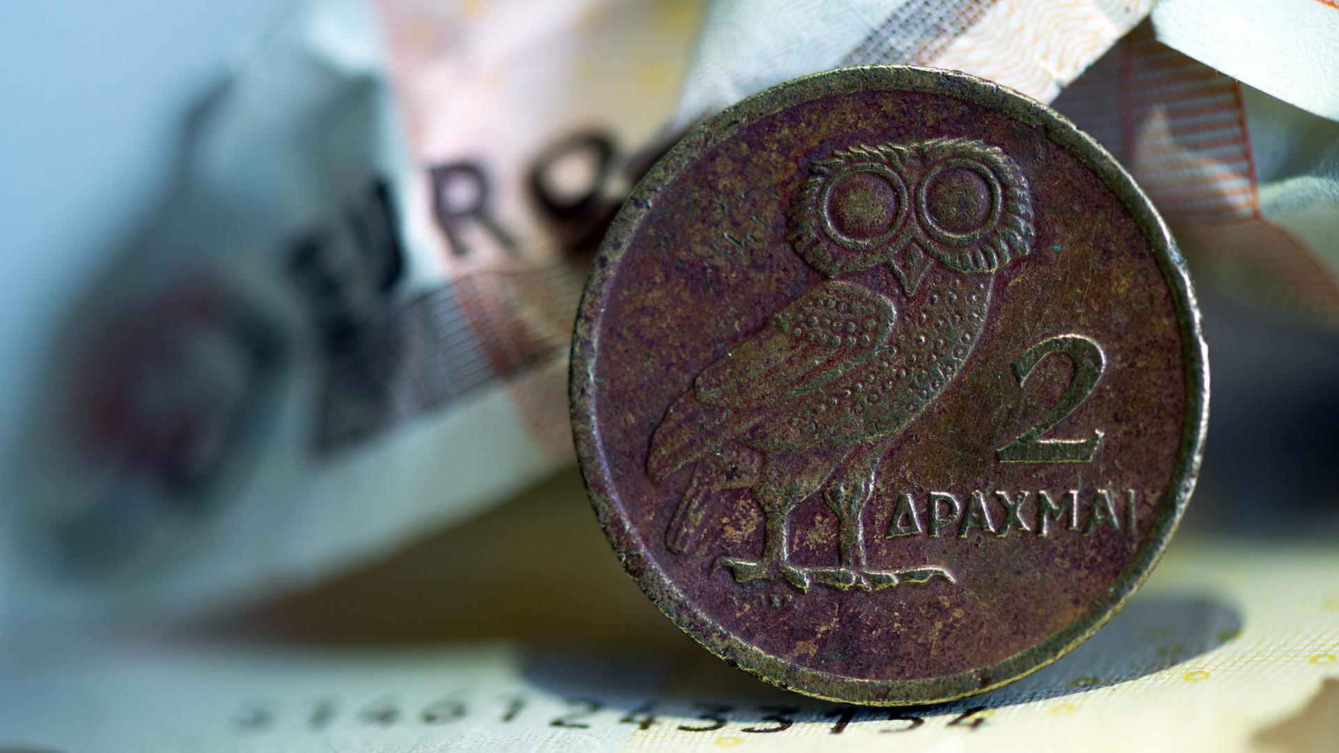 Eine griechische Drachmenmünze liegt auf geknüllten Euroscheinen. Eine griechische Drachmenmünze liegt auf geknüllten Euroscheinen.