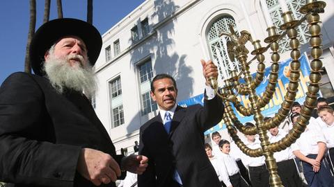Ein Bürgermeister und ein Rabbi präparieren die Kerzen auf einem Menoarah während der Chabad Chanukka-Feier in den USA.