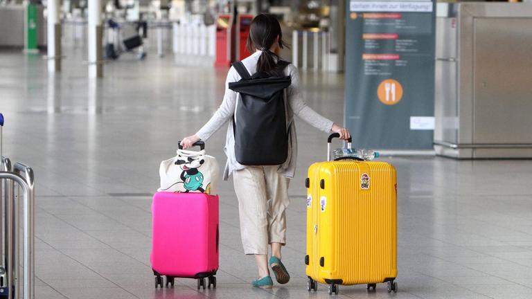 Eine einsame Reisende mit zwei großen Koffern menschenleeres Terminal 1 in der Abflughalle B im Flughafen Frankfurt, Hessen, Deutschland