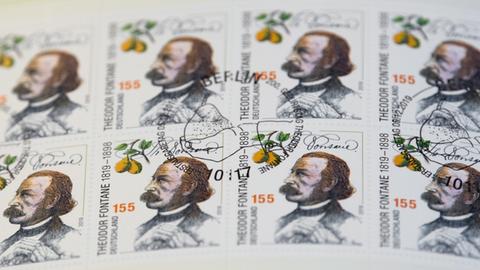 Ansicht von gestempelten Briefmarken «200. Geburtstag Theodor Fontane» während der Präsentation in Neuruppin. Auf der Briefmarke ist ein zeitgenössisches Portrait von Theodor Fonate zu sehen, seine Unterschrift, sowie ein Birnenzweig mit zwei Früchten.