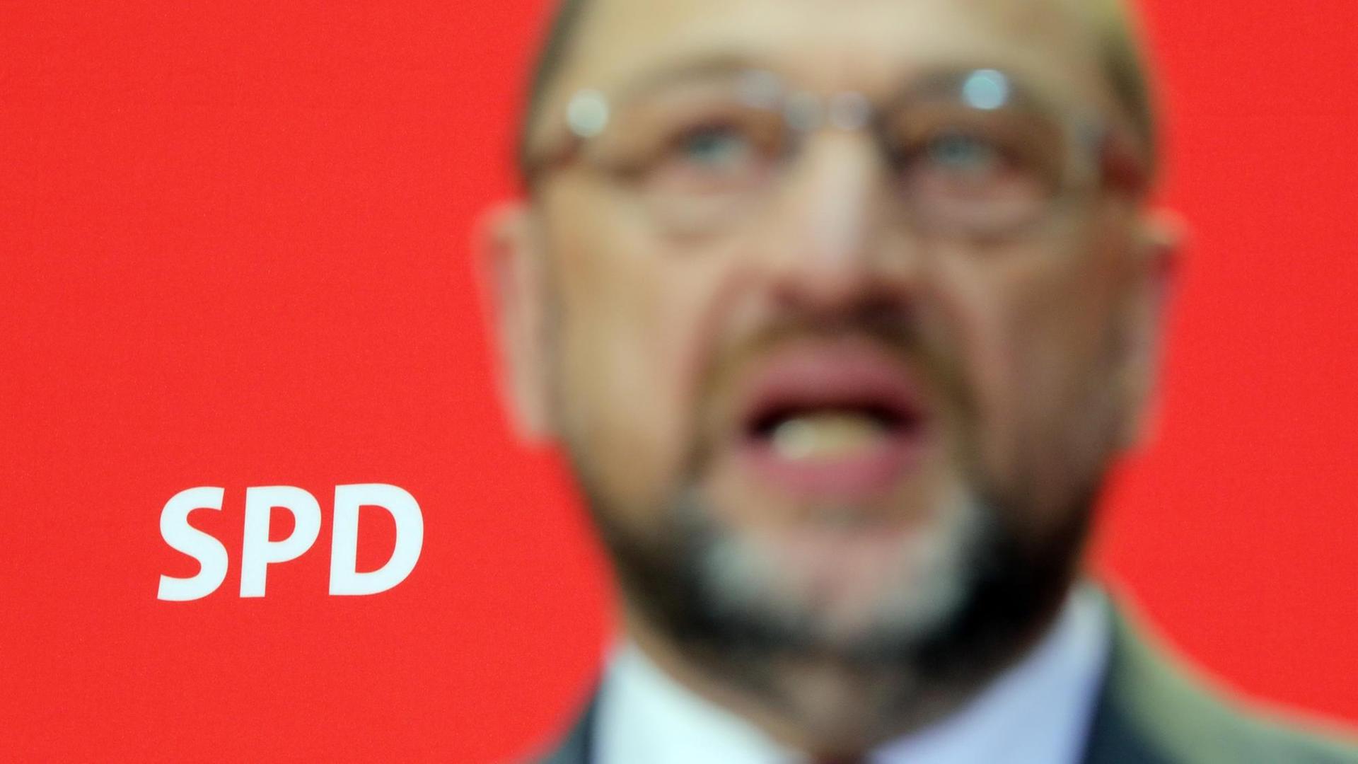 Martin Schulz verschwommen vor rotem Hintergrund mit den Buchstaben SPD scharf gestellt.