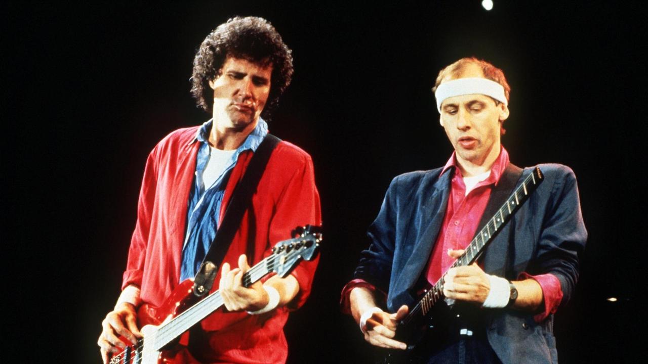 Der Sänger Mark Knopfler der bitischen Rockgruppe "Dire Straits" mit Stirnband, rotem Hemd und Jackett und der Bassist John Illsley - dunkle Locken und rote Jacke - bei einem Auftritt in Helsinki/Finnland auf der Bühne (Aufnahme vom 28.10.1985). Der Sänger Mark Knopfler der bitischen Rockgruppe "Dire Straits" mit Stirnband, rotem Hemd und Jackett und der Bassist John Illsley - dunkle Locken und rote Jacke - bei einem Auftritt in Helsinki/Finnland auf der Bühne (Aufnahme vom 28.10.1985).